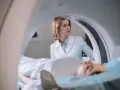 Lekarka nadzoruje badanie rezonans serca. Pacjent leży na stole diagnostycznym wewnątrz aparatu MRI.