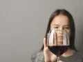 Kobieta odrzuca kieliszek z czerwonym winem, symbolizując walkę z pokusą, która może prowadzić do dawki śmiertelnej alkoholu.