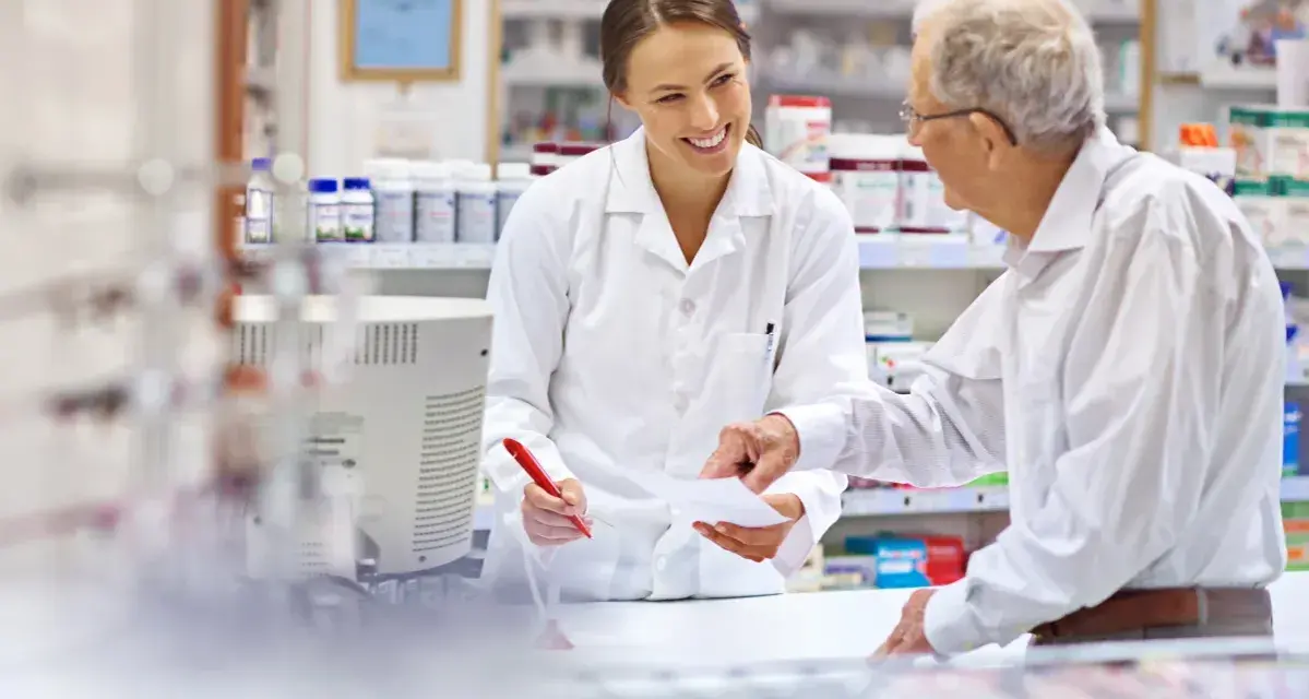 Farmaceutka pomaga seniorowi zrealizować receptę na darmowe leki.