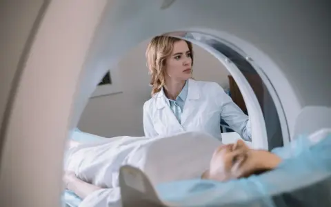 Lekarka nadzoruje badanie rezonans serca. Pacjent leży na stole diagnostycznym wewnątrz aparatu MRI.