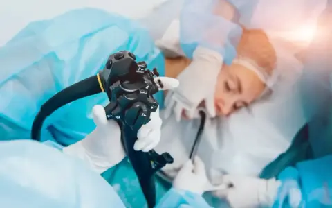 Gastroskopia ze znieczuleniem w toku. Lekarz trzyma endoskop, przygotowując się do badania pacjenta.