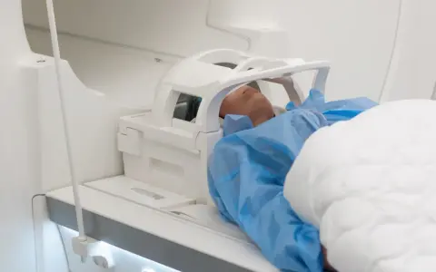 Pacjent leży w aparacie do rezonansu magnetycznego głowy, przygotowany do badania.