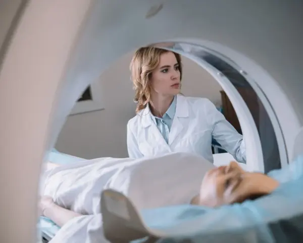 Lekarka nadzoruje badanie rezonans serca. Pacjent leży na stole diagnostycznym wewnątrz aparatu MRI.