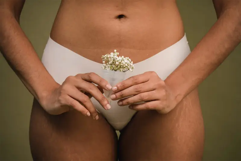 Kobieta trzyma kubeczek menstruacyjny z kwiatami, symbolizujący naturalność cyklu. To część odpowiedzi na pytanie: co to okres.
